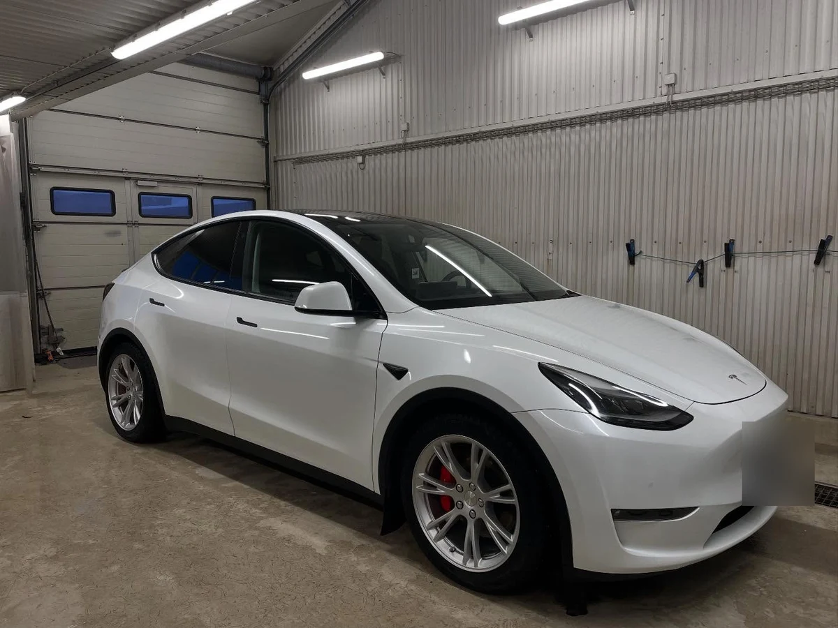 Vit Tesla Model Y efter rekond, fotograferad snett framifrån